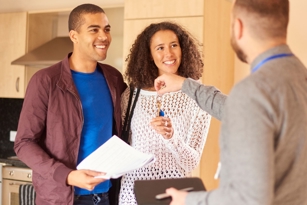 A landlord handing over the keys of rental property to two new tenants