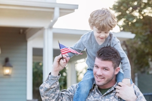 A military service member holds a child on their shoulders, representing a military family move to Fort Gordon in Augusta, GA.