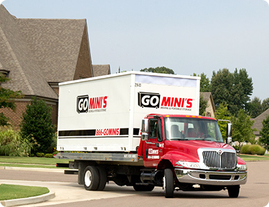 Go Mini's truck driving a portable storage container through a neighborhood