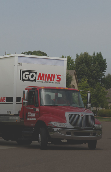 A red truck transporting a large white Go Mini's portable storage container
